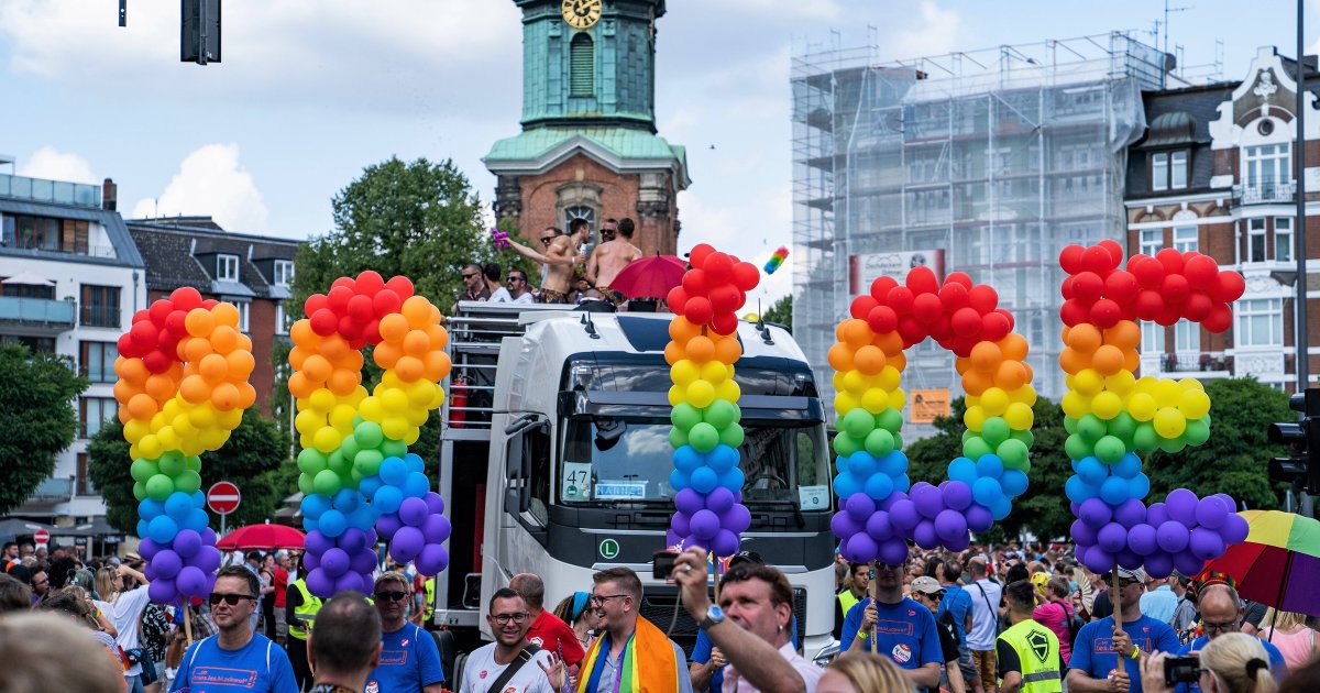 Crowds waving rainbow flags and participating in Hamburg Pride under heavy police presence.